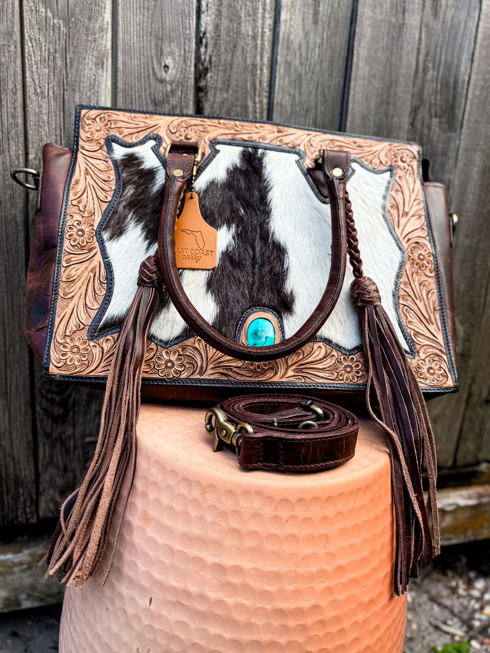 Front view of western cowhide tote with hand-tooled floral leather and turquoise concho accent