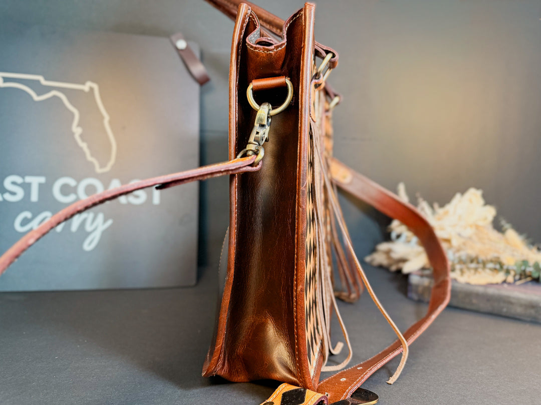 Side view of the Checkmate cowhide and checkered leather tote with sturdy straps.