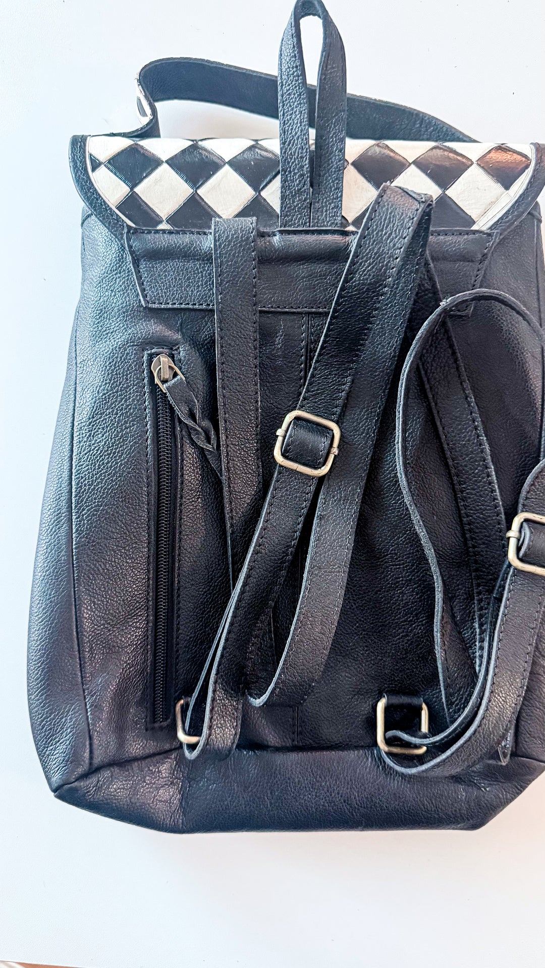 Back of Speed Check black leather backpack with adjustable shoulder straps, top handle and vertical concealed carry zipper pocket.