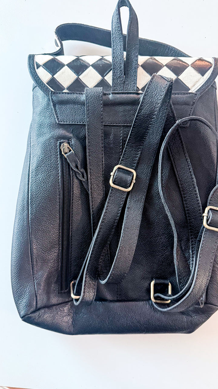 Back of Speed Check black leather backpack with adjustable shoulder straps, top handle and vertical concealed carry zipper pocket.