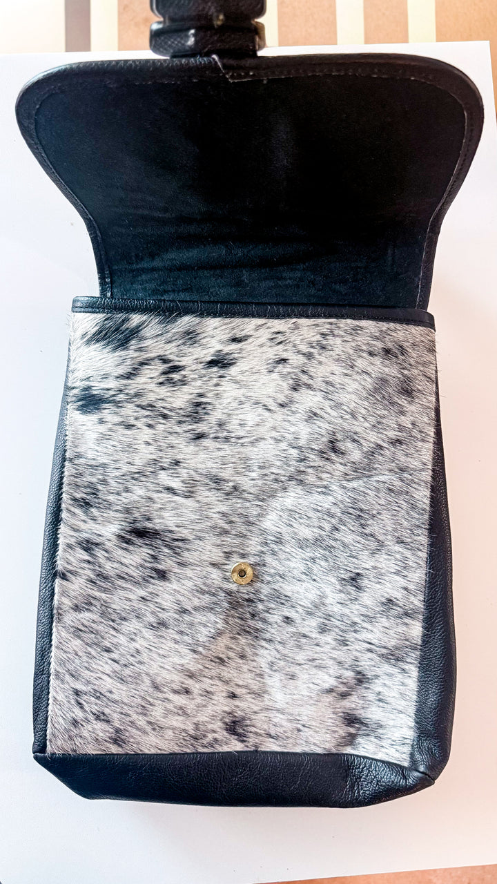 Speed Check cowhide backpack with flap lifted to reveal black and white salt-and-pepper hair-on cowhide and magnetic snap closure.