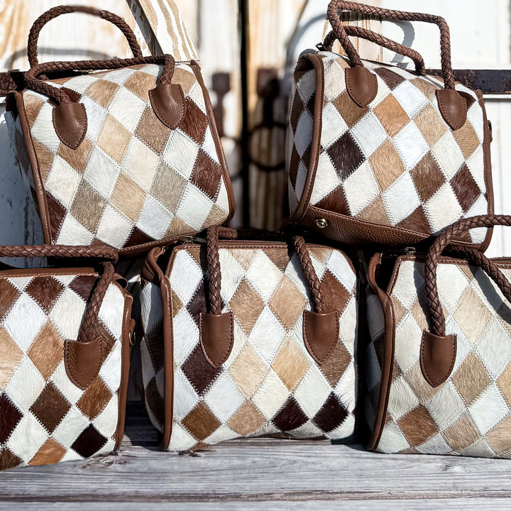 Five Soft & Strong diamond patchwork cowhide satchels with cream, tan and brown geometric patterns and braided leather handles.