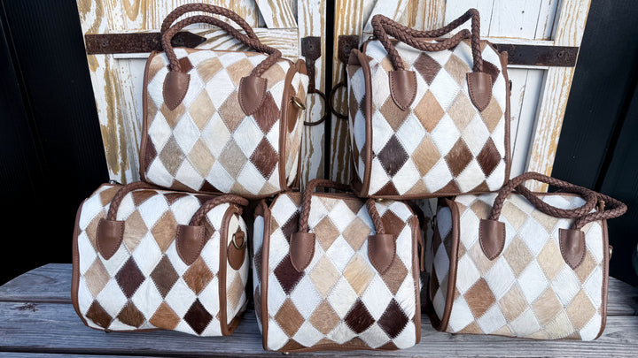 Four Soft & Strong cowhide satchels displayed together showing variations in cream, tan and brown diamond patchwork patterns.