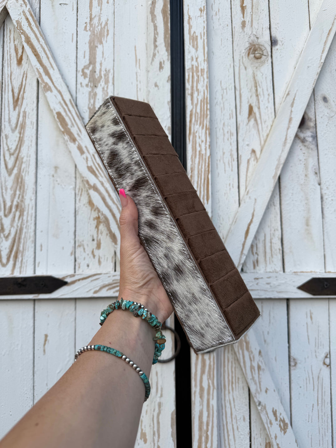 Hand holding up a rectangle shaped genuine Cowhide ring display holder with 10 velvet lined slots with room to display multiple rings 